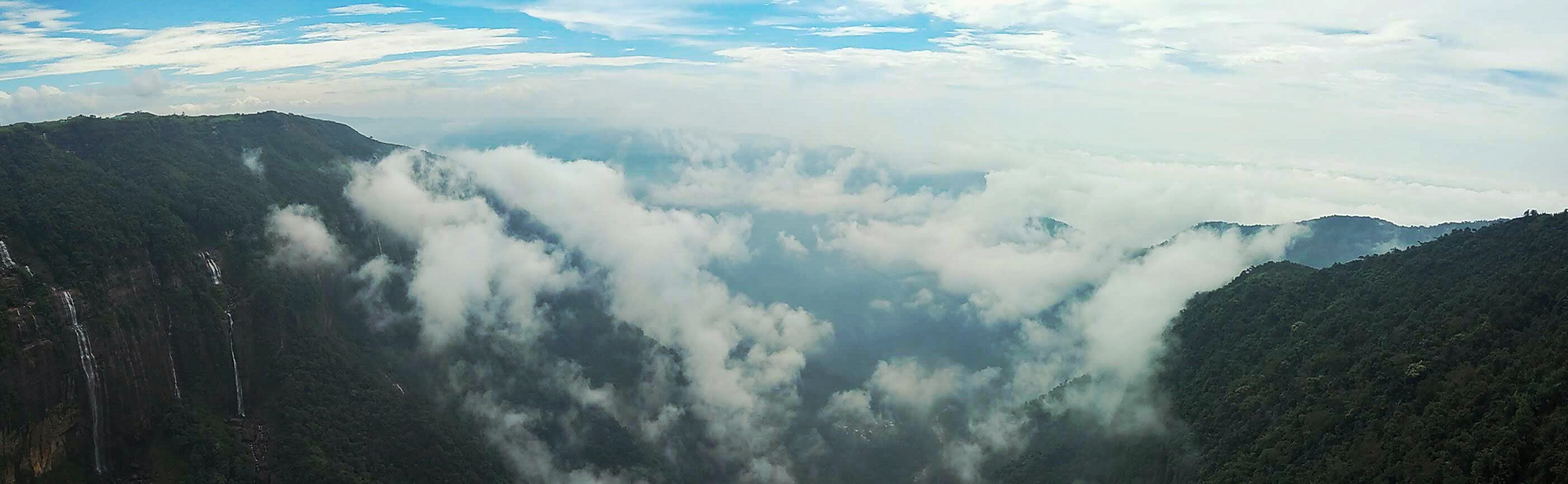 A panoramic view of green valleys and a massive cliff side in Meghalaya